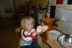 ein Kind mahlt mit einer Handmühle Mehl